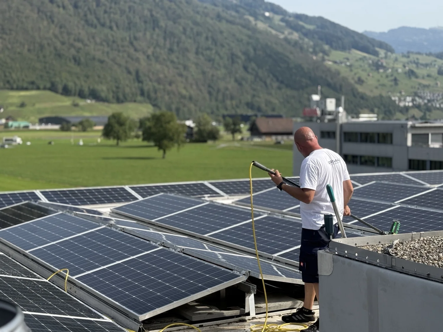 Gremax-Mitarbeiter reinigt eine Photovoltaikanlage auf einem Flachdach